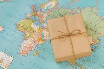 International shipping. Cardboard box on the geographical map background