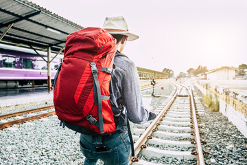 Alone travel concept. Young backpacker and hat at the train station and looking on the map for plan to travel.