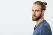 © Cookie Studio - Close up of manly handsome guy with fashionable hairstyle and beard looking in camera, holding head in three quarters with serious expression.