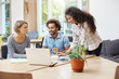 © Cookie Studio - Three young prospective entrepreneurs sitting at library, discussing business plans and company's profits, making business research with laptop, looking through information on tablet.