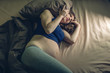 © Artem - Pregnant woman feeling pain in her belly lying in bed with insomnia at night. Concept of pregnancy and health