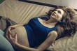 © Artem - Pregnant woman feeling pain in her belly lying in bed with insomnia at night. Concept of pregnancy and health