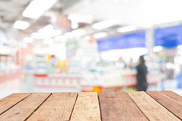 Wooden board empty table in front of blurred convenience store cashier background with bokeh