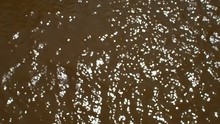Brown Water River Background With Bright Sunlight Reflecting On Small Wave Moving, Top View