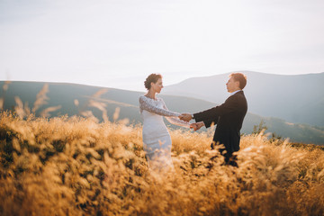 Wall Mural - Beautiful newlyweds pose in a field with golden wheat