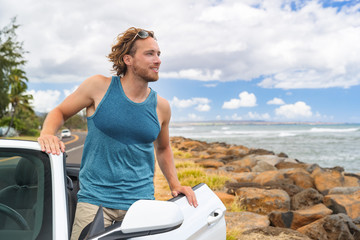 Wall Mural - Driving man on road trip convertible car travel looking at nature scenery from cabriolet sports automobile on summer vacation. Happy young male traveler in tropical destination.