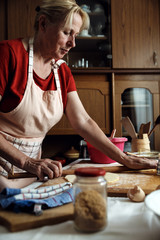 Wall Mural - Senior female baker kneading dough with rolling pin in kitchen.