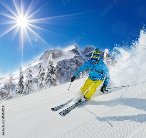 Plakat Młody człowiek narciarz biegnie w dół stoku w alpejskich górach