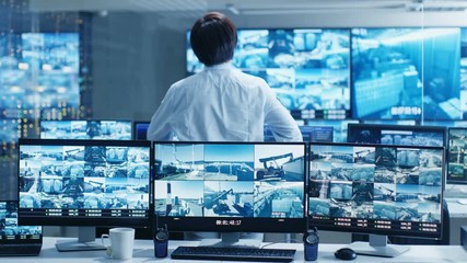 Leinwandbilder - In the Security Control Room Officer Monitors Multiple Screens for Suspicious Activities. He Guards Internationally Important Logistics Facility. Shot on RED EPIC-W 8K Helium Cinema Camera.