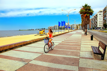 Woman biking on the boulevard along Pocitos beach in Montevideo, Uruguay.