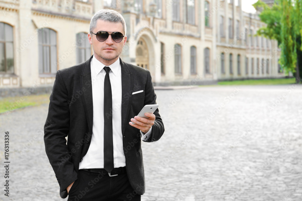 Elegant businessman using mobile phone outdoors