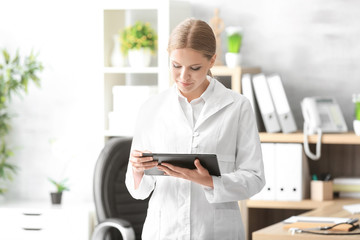 Poster - Young female receptionist holding tablet computer in hospital