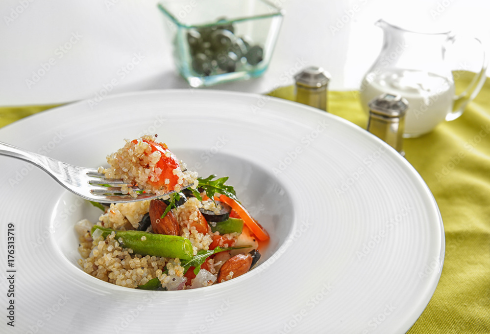 Fork and plate with delicious quinoa salad, closeup