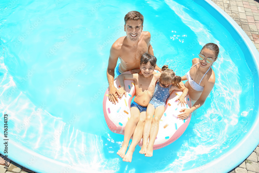 Happy family with inflatable donut in swimming pool