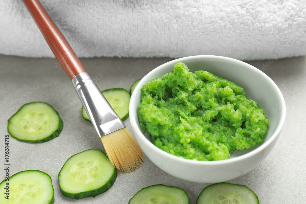 Bowl with cucumber mask and brush on table