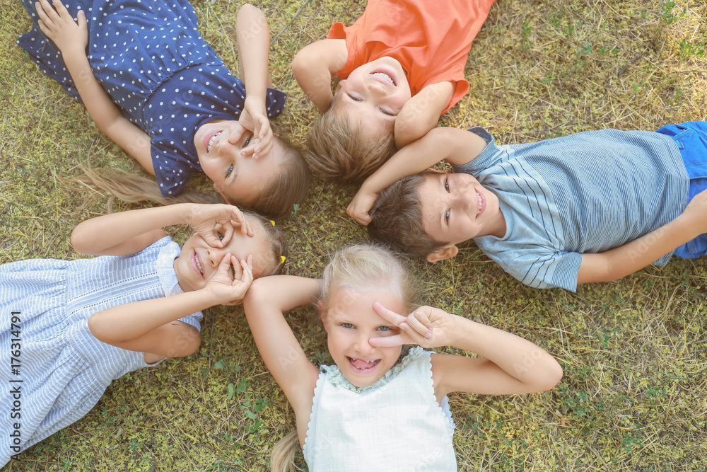 Group of children lying on green grass in park