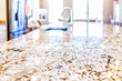 New modern faucet and kitchen room sink closeup with island and granite countertops in model house, home, apartment