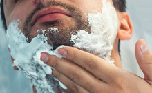 A Young Man Is Shaving In The Morning, Smiling. On The Face There Is A Lot Of Foam For Shaving. Toning