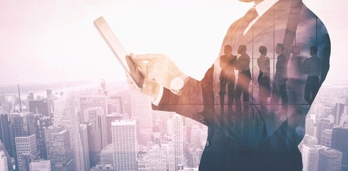 Poster - Composite image of businessman in suit using digital tablet