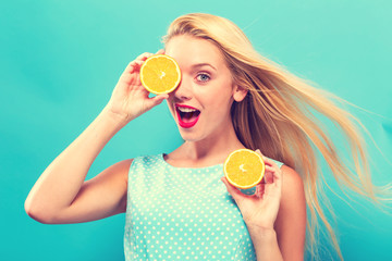 Happy young woman holding oranges on a solid background