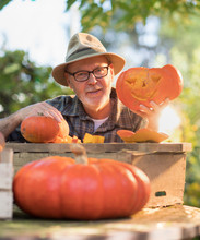 Man Showing On Camera A Pumpkin He Has Just Carve For Halloween On The Table In His Garden.