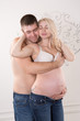 © olharozova - Beautiful pregnant couple in love on the background. Hands of husband on the tummy of his pregnant wife. Young man tenderly stroked pregnant belly of his wife. Husband kissing pregnant belly.