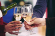 © DragonImages - Close-up of three unrecognizable people toasting with wine glasses