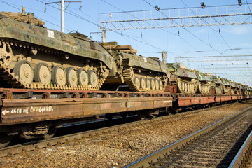 Cargo train carrying military tanks on railway flat wagons