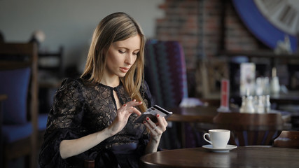 A young woman who went into a restaurant to drink coffee and dine enters the details of her bank card into the mobile Internet to pay for parking her car