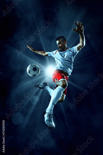 Zdjęcie XXL Gracz piłki nożnej wykonuje grę akcji na ciemnym tle. Gracz nosi niemarkowy mundur sportowy.