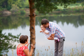 happy married couple with child on the river bank