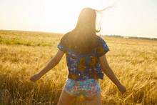 A girl walking and posing in the field of wheat enjoying sunset