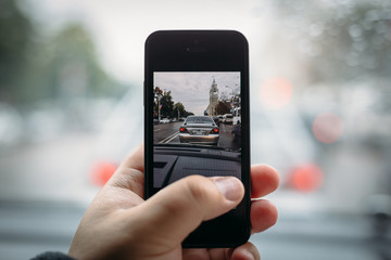 Man shooting city traffic by smartphone in hand from his car, toned