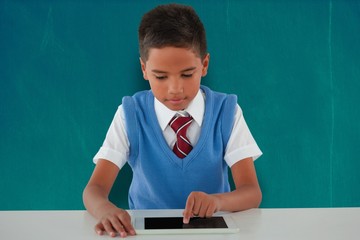 Poster - Composite image of schoolboy using digital tablet at table