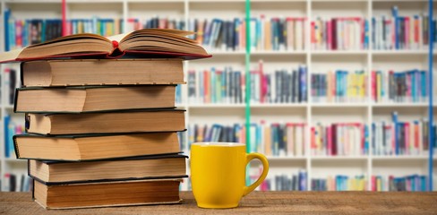 Canvas Print - Composite image of stack of books by yellow mug on wooden table