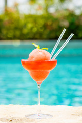 Wall Mural - Frozen strawberry margarita cocktail at the edge of a resort pool.  Concept of luxury vacation