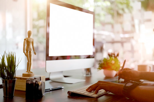 Creative businessman drawing on graphic tablet while using modern desktop computer in office. Blank screen for graphic display montage.