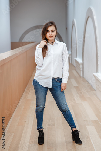 Portrait Of Sexy White Caucasian Brunette Young Beautiful Girl Woman With Long Dark Hair In White Shirt And Blue Jeans Young Girl Standing Indoor In Hall At College University Stock Photo Portrait Of Sexy White Caucasian Brunette Young Beautiful Girl Woman With Long Dark Hair In White Shirt And Blue Jeans Young Girl Standing Indoor In Hall At College University Stock Photo