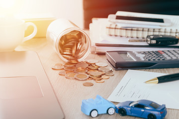 Car insurance concept:Car claim form with car toy crash on desk with Money flow out of jar coin bank ,warm tone filter