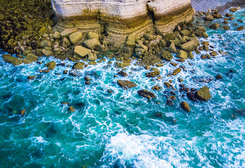 Wall Mural - Drone view of waves hitting sea shore and rocks