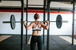 © Alina Schessler - Rear view of woman lifting barbell in the gym