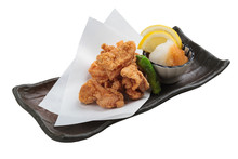 Isolated Japanese Deep Fried Chicken (Karaage) With Cooking Paper Served With Tempura Sauce (Tentsuyu) Mixing Mince Radish And Sliced Of Lemon In Black Plate.