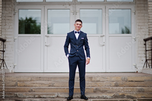 Portrait of a handsome high school graduate in stylish tuxedo posing on the stairs on the prom Canvas-taulu
