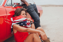 Couple Sitting Out Of A Vintage Red Car In The Desert