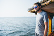 © Alejandro Moreno de Carlos/Stocksy - Young man wearing sunglasses looking from a house boat. Kerala backwaters, India