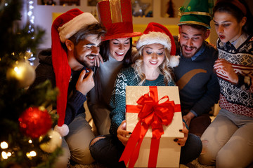 Wall Mural - smiling friends opening magic Christmas gift.