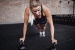 © Flamingo Images - Focused young woman doing pushups with weights in a gym