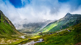 Fototapeta Na sufit - Landscape view of a beautiful green valley surrounded with mountains, clouds on the top. Spring, Grossvenediger, Hohe Tauern, Alps, Austria.