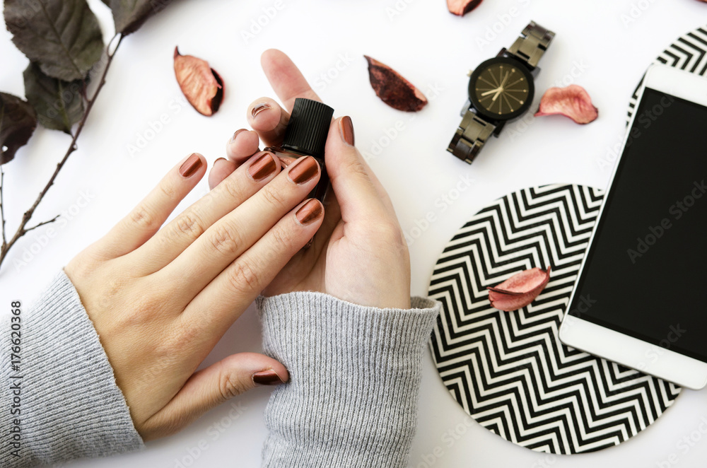 Fotografiet Female hands with nail polish on white background with mobile phone, watch and autumn petals