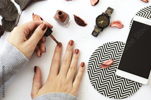 Canvastavla Female hands with nail polish on white background with mobile phone, watch and autumn petals